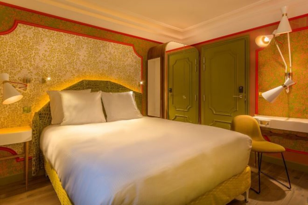 Ein Hotelzimmer mit Bett, Schreibtisch, Stuhl und Kleiderschrank.