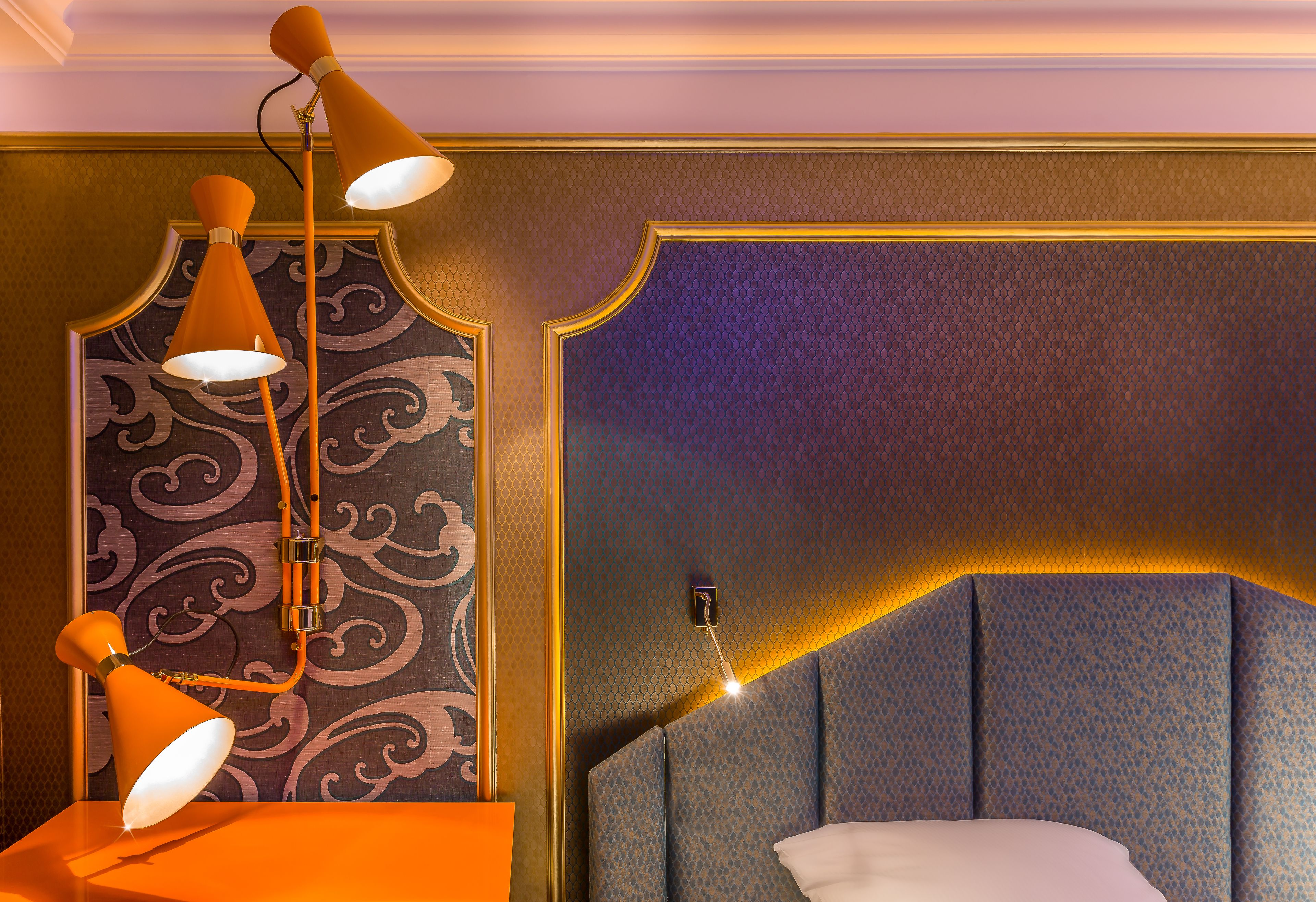 A room with a bed, a nightstand, and a wall with a decorative pattern.