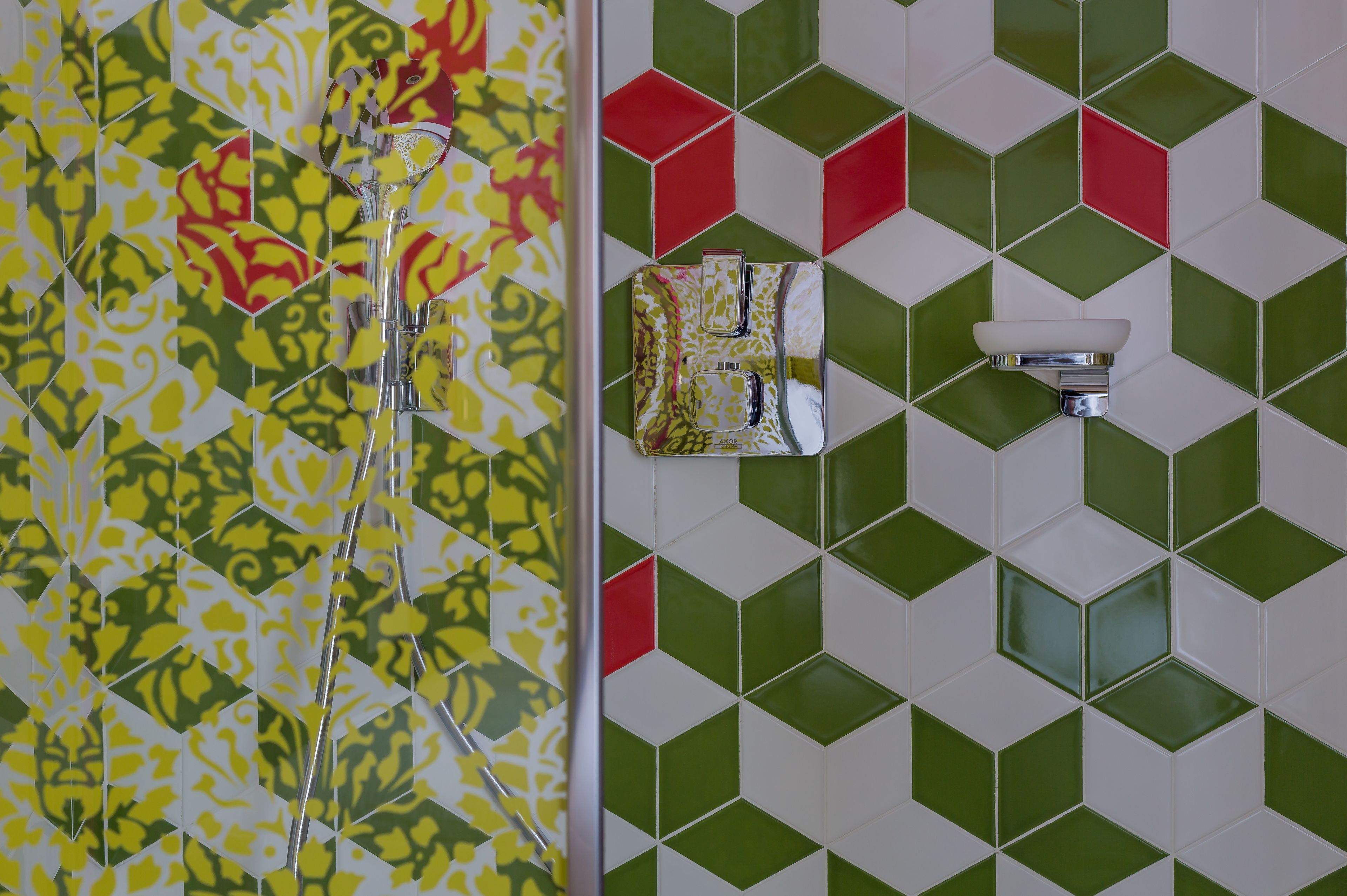 Un baño con baldosas estampadas, una ducha y un aplique de pared.