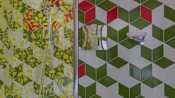 Un baño con baldosas estampadas, una ducha y un aplique de pared.