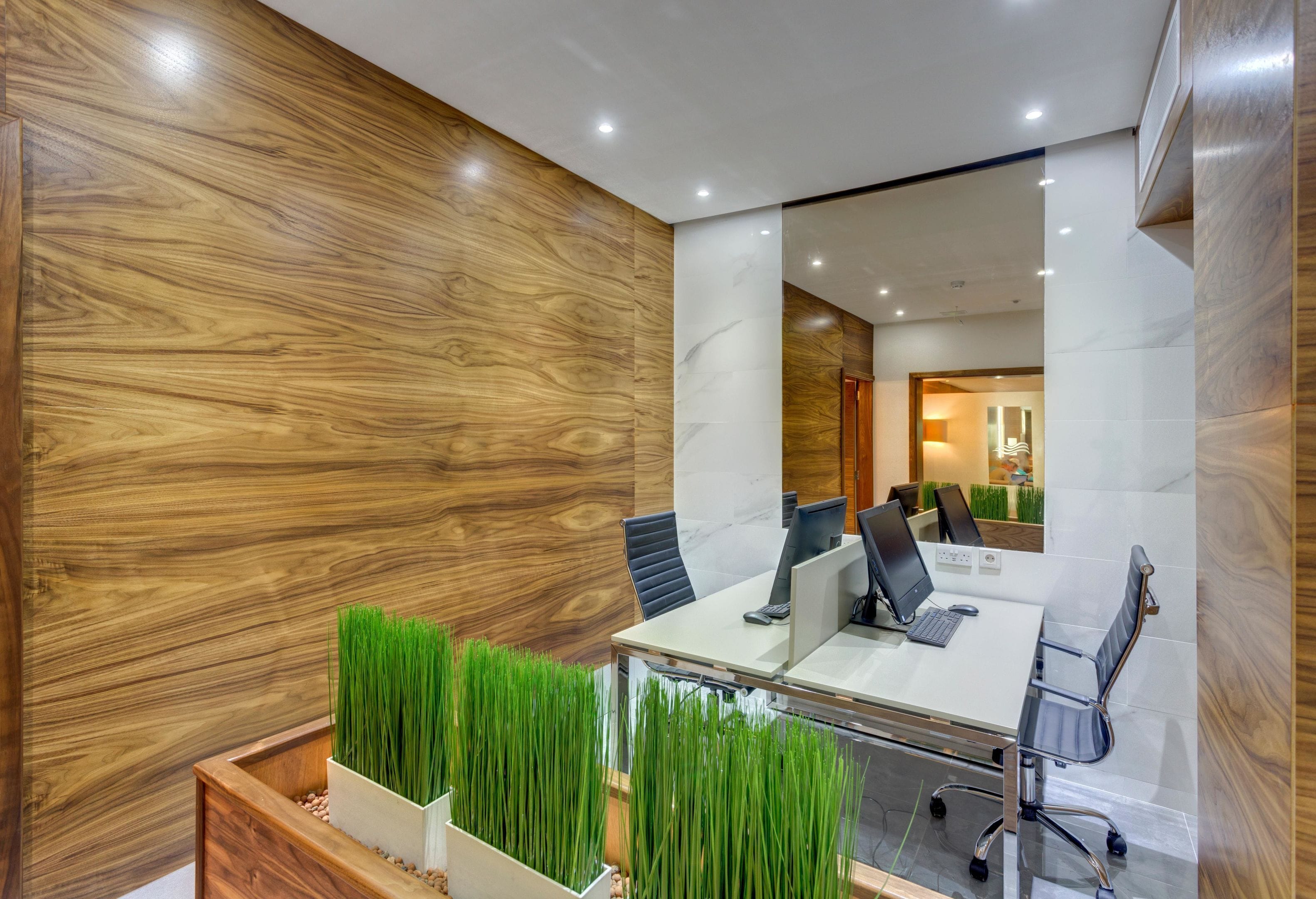 A modern office space with a glass table, black office chairs, and a wooden accent wall.