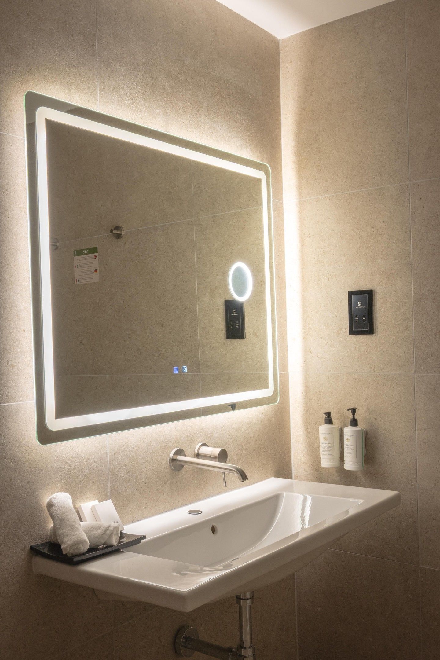 Un baño con un espejo grande, un lavabo y dos botellas de champú.