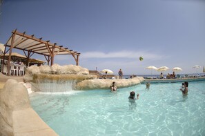 A pool area with clear water, a wooden pergola, and umbrellas. - The Preluna Hotel (Sliema)