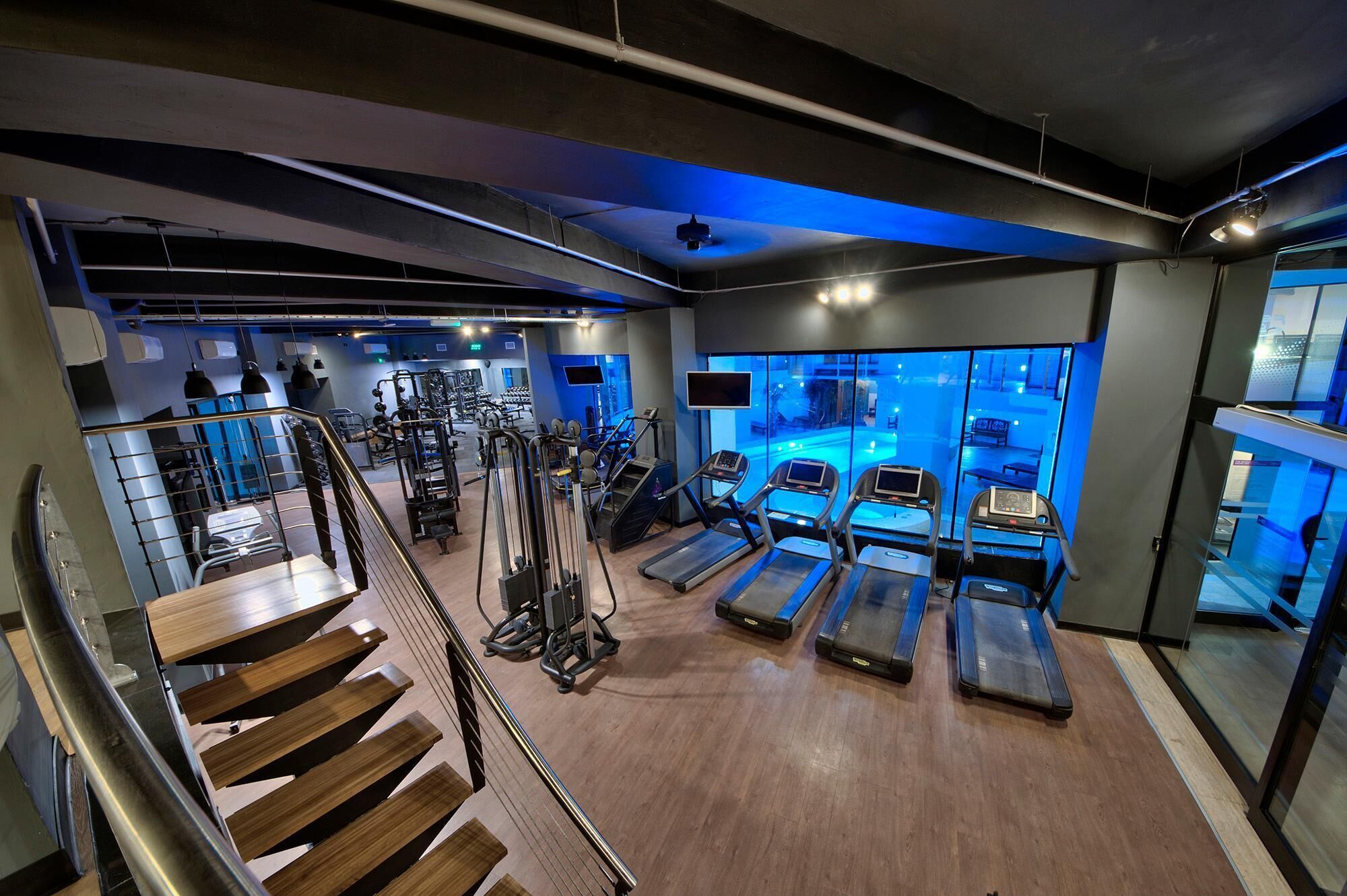 Une salle de sport équipée de tapis de course, d’appareils de musculation et d’un espace piscine.