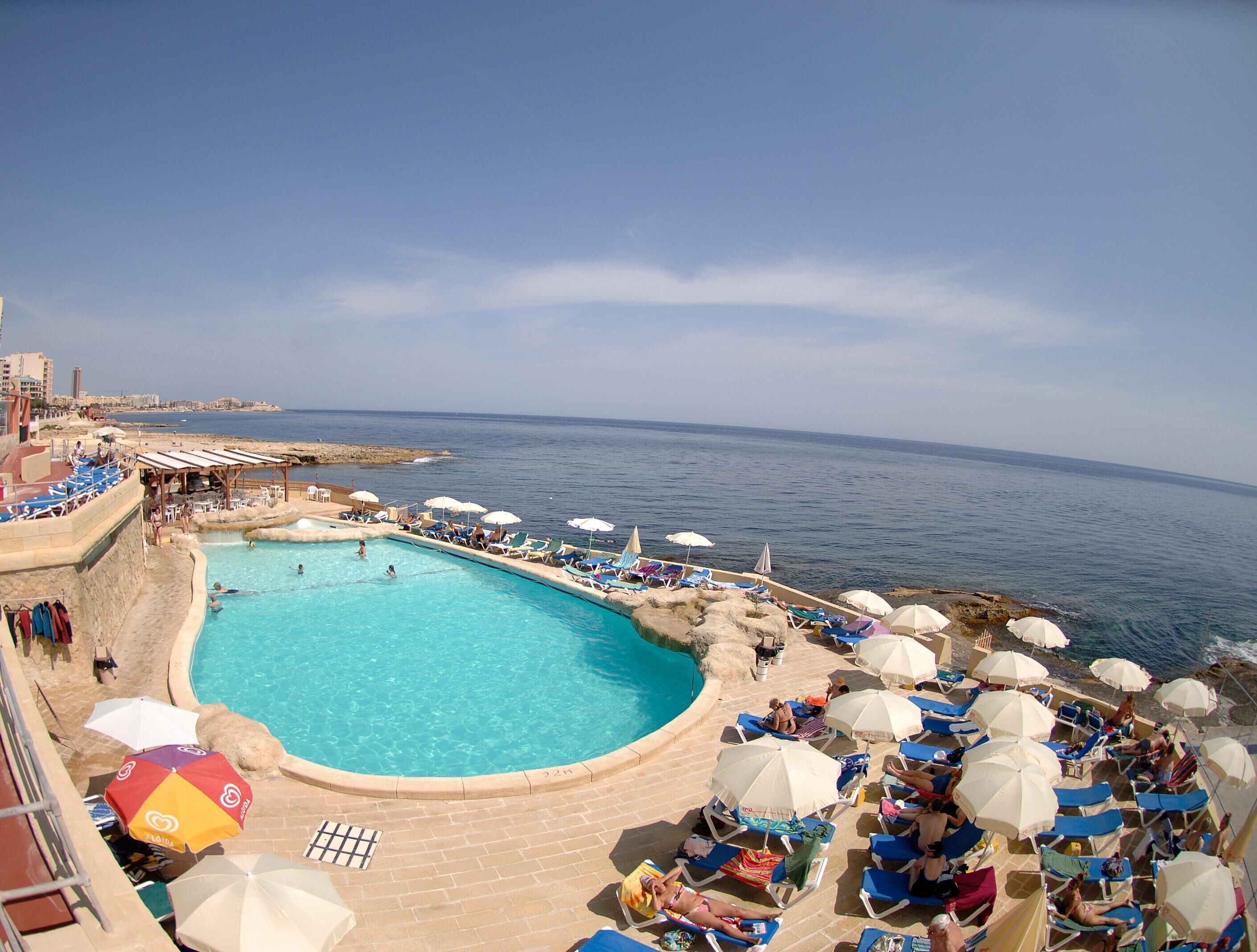Una piscina cubierta, una piscina al aire libre, sombrillas, tumbonas