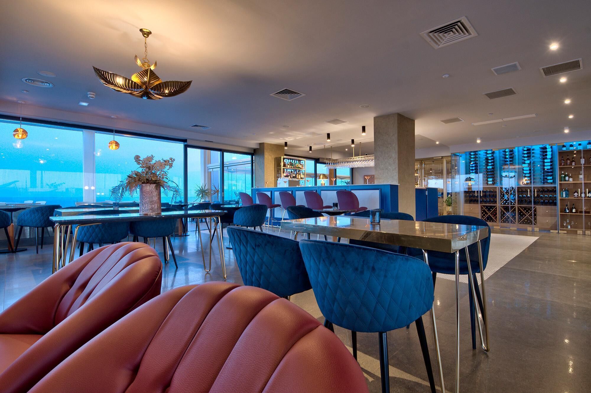 Un restaurante moderno con barra, ventanas amplias y vistas a la ciudad.