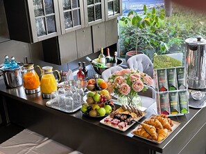 Un bufé de desayuno con diversas opciones de comida y bebidas, y vista a zonas verdes al exterior.