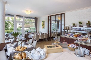 Zona pranzo con tavoli, sedie e un buffet con cibo e bevande.