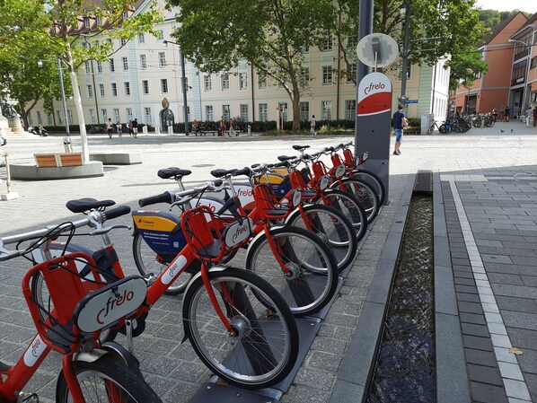 A row of red bicycles with 'frelo' branding parked along a sidewalk.