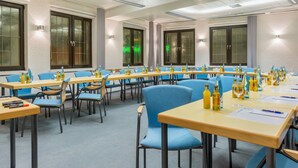 A conference room with long tables, blue chairs, and various items like bottles and papers on the tables.