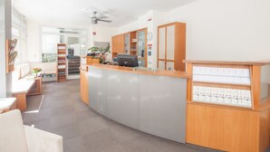 Una zona de recepción con un mostrador de madera, una computadora y un reloj de pared.