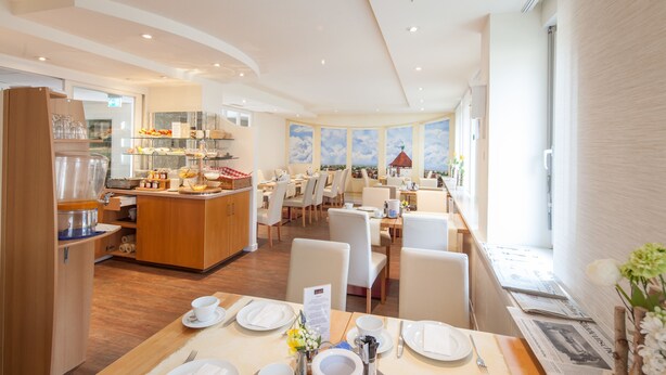 Comedor de hotel con bufé, disposición de mesas y vistas a la ciudad.