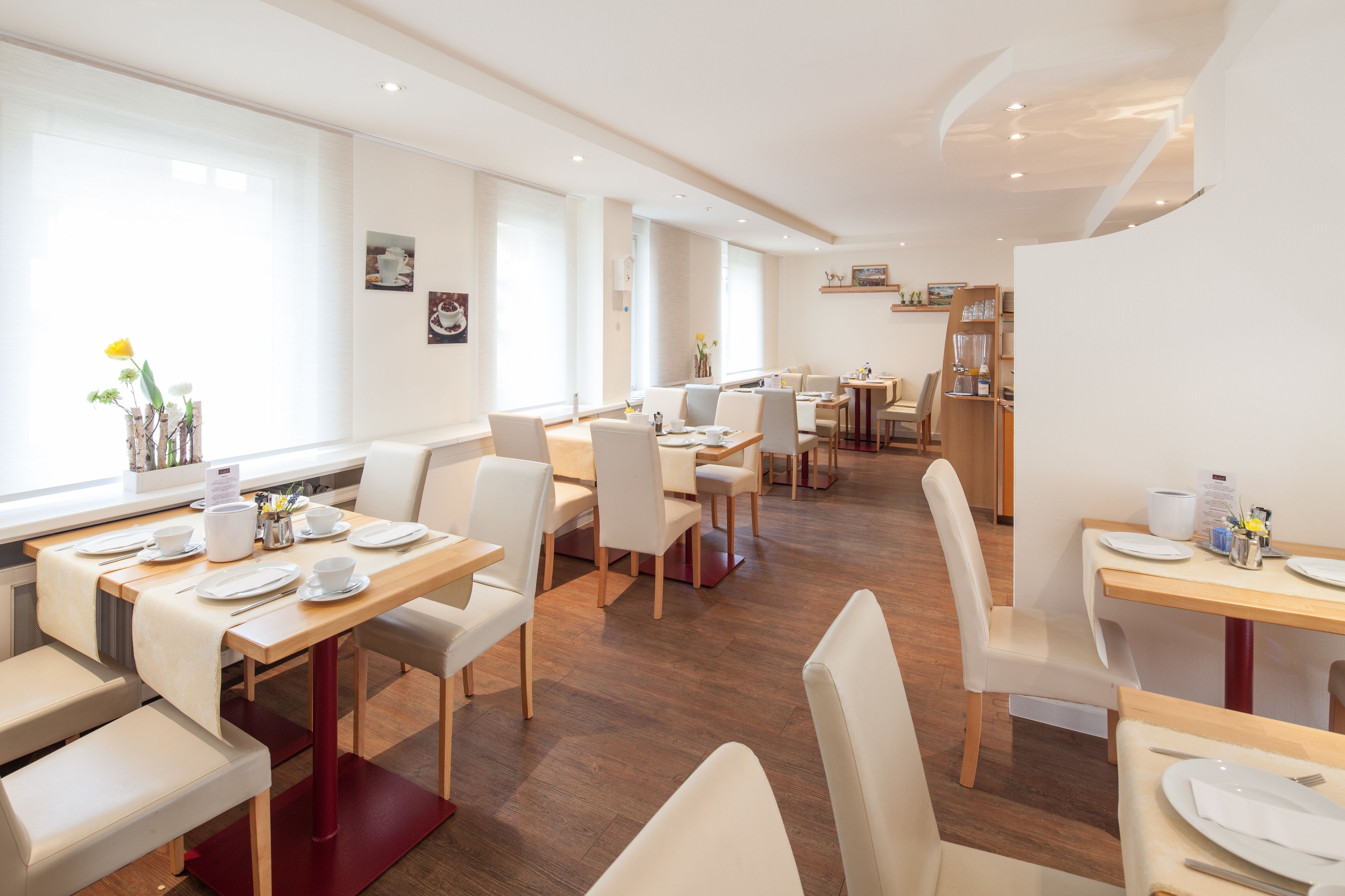 A modern dining area with multiple tables and chairs, large windows, and a clean, minimalist design.