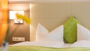 Habitación de hotel con cama, almohadas, una manta verde y un aplique de pared.