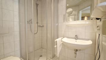 A modern bathroom with a glass-enclosed shower, a white sink, and a mirror above the sink.