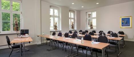 Une salle de conférence équipée de longues tables, de chaises et d’un projecteur.