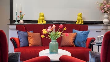 A red sofa with patterned cushions, a vase with flowers, and two yellow lion statues on a black countertop.