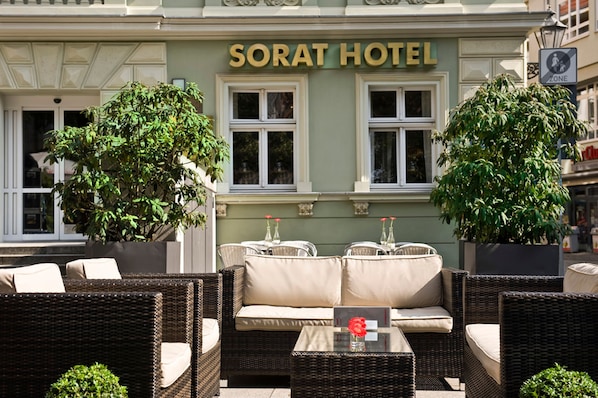 The exterior of Sorat Hotel with outdoor seating and large potted plants.