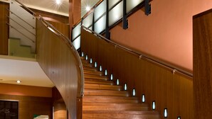 A curved wooden staircase with glass railings and illuminated steps. - Sorat Insel-Hotel Regensburg (Regensburg)