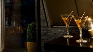 A restaurant interior with a view of a cathedral through a window, a table with two martini glasses, and a small plant on the table. - Sorat Insel-Hotel Regensburg (Regensburg)