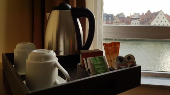 Una bandeja con una tetera, tazas y artículos de tocador junto a una ventana con vistas al río.