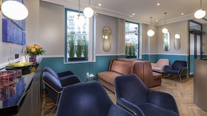 A modern interior with seating, a bar area, and large windows offering city views. - Hôtel Elysa - Luxembourg (Paris)