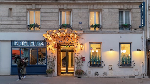A hotel facade with a classic architectural style, featuring a prominent entrance with decorative lighting and potted plants. - Hôtel Elysa - Luxembourg (Paris)