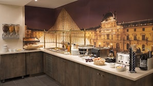 A breakfast bar with a view of a historic building, equipped with a coffee machine, toaster, and various breakfast items. - Hôtel Elysa - Luxembourg (Paris)
