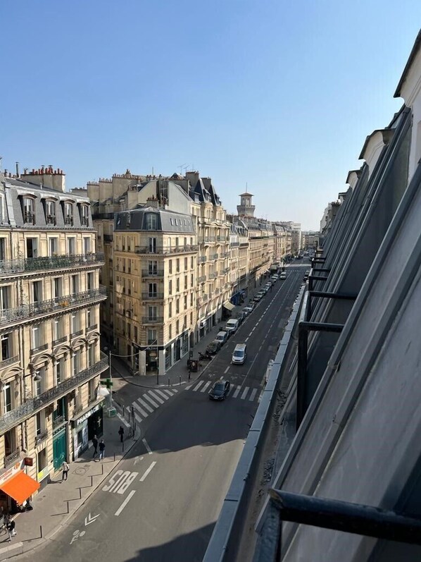 A street view with buildings on both sides, a clear sky, and a pedestrian crossing.