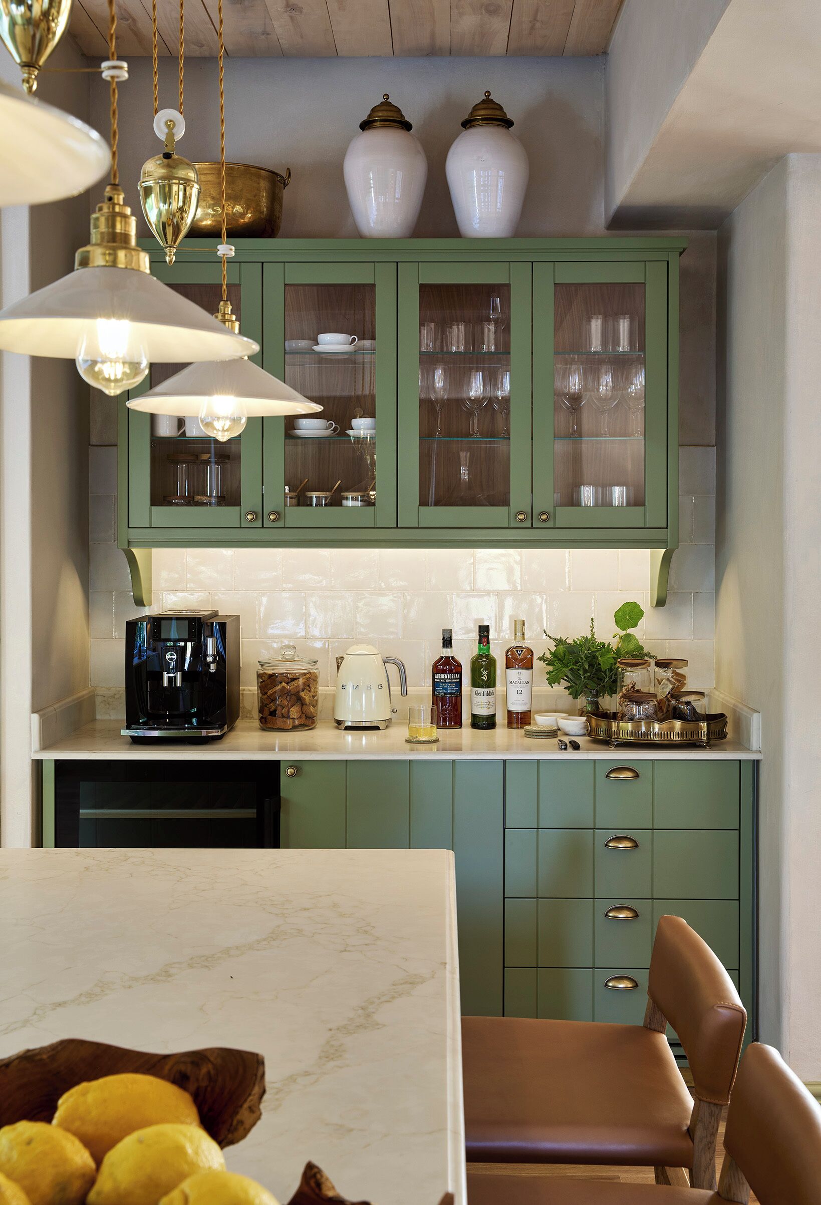 A kitchen with green cabinets, a coffee machine, and various kitchen items on the counter.