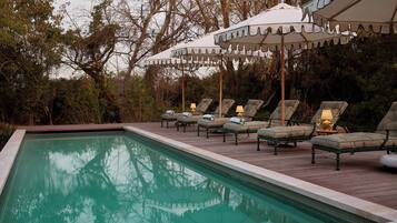 A swimming pool with lounge chairs and umbrellas.