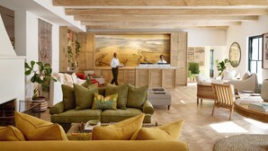 Amplia sala de estar con techo alto, un cuadro grande de paisaje desértico y un mostrador de recepción.