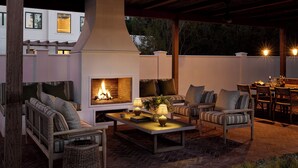 Un patio al aire libre con chimenea, asientos y zona de comedor.