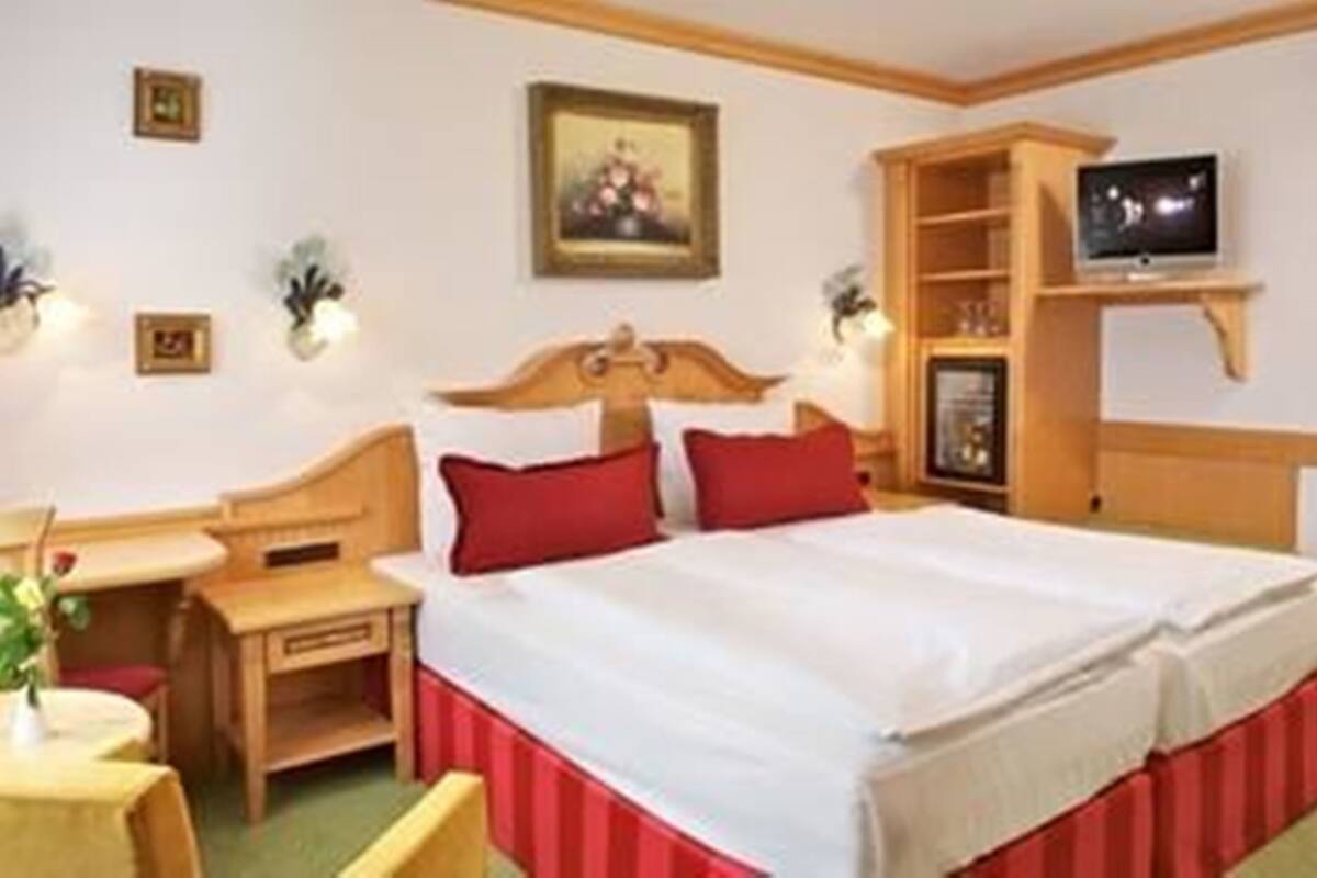 A hotel room with a bed, a television, a desk, and a chair.