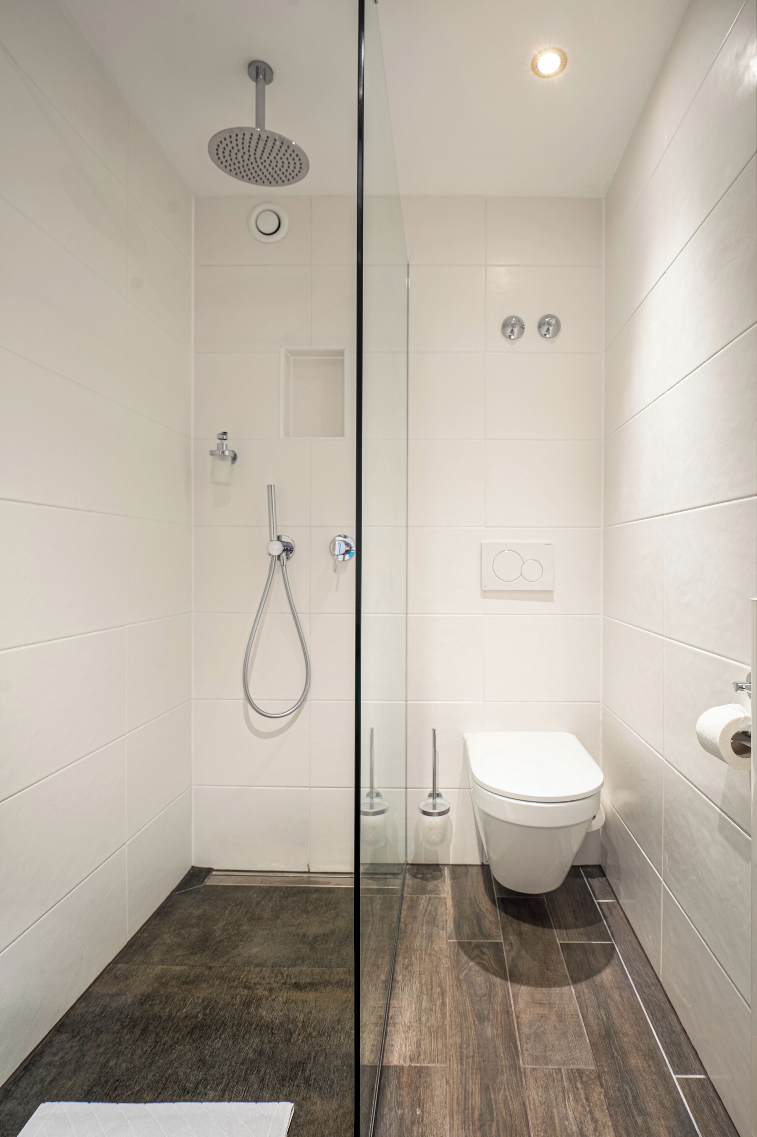 A modern bathroom with a glass shower enclosure, a toilet, and a sink.