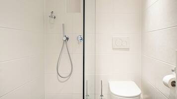 A modern bathroom with a glass shower enclosure, a toilet, and a sink.