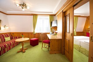 Una habitación acogedora con un escritorio de madera, un sofá, una silla roja y una cama.