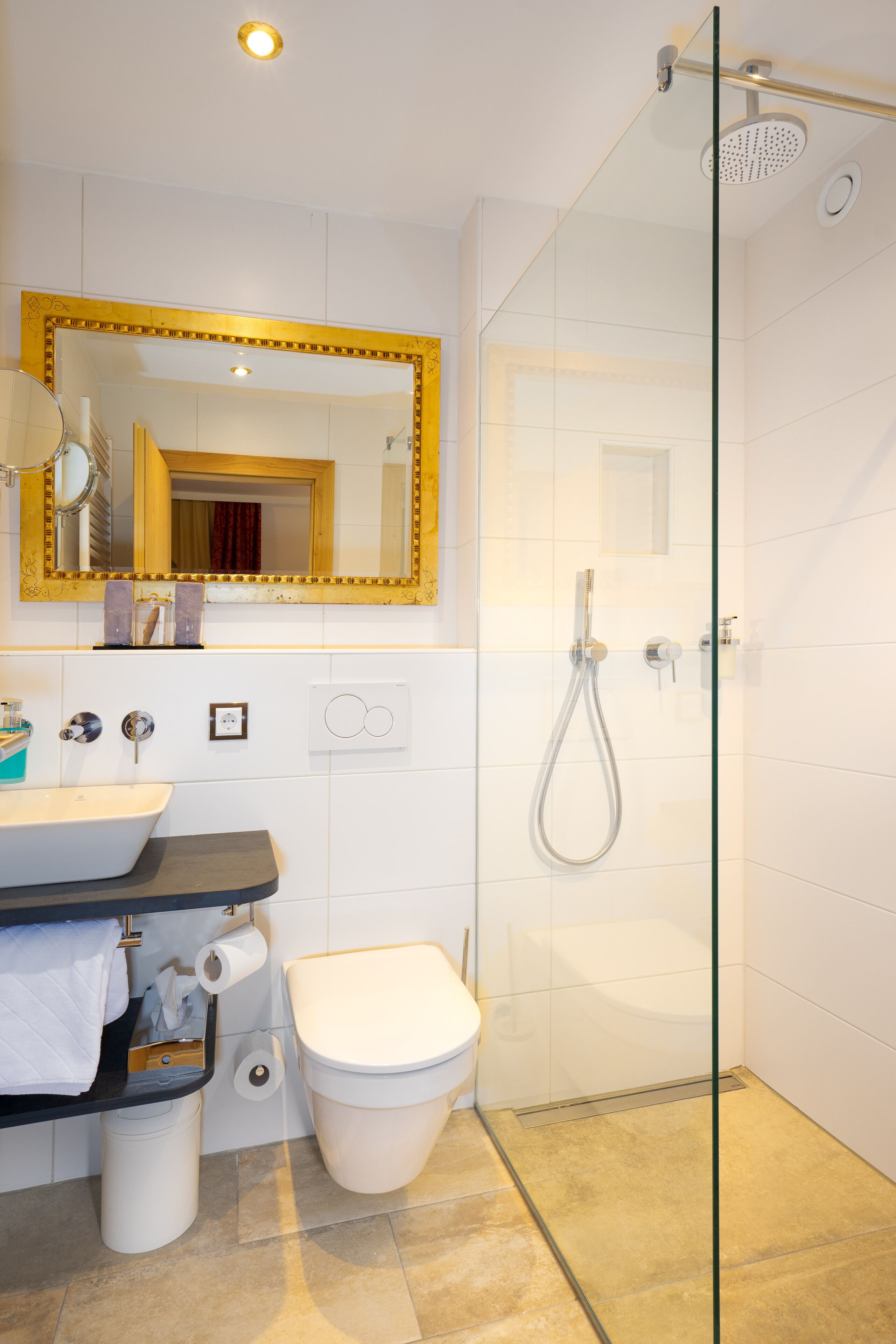 Un baño moderno con ducha de vidrio, un lavamanos blanco y un inodoro.