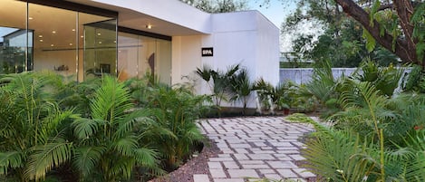 Un edificio moderno con insegna dello spa, immerso nel verde e con un vialetto in pietra.