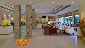 A spacious hotel lobby with marble columns, a reception desk, seating area, and large windows offering a view of the outdoors. - Radisson Hotel Khajuraho (Rajnagar)