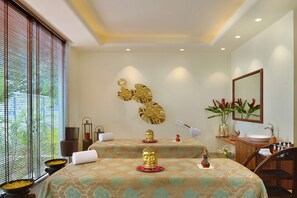 A hotel room with two beds, a large window with blinds, a decorative wall piece, a sink, and a mirror. - Radisson Hotel Khajuraho (Rajnagar)