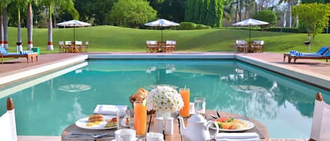 Una piscina al aire libre, sillones reclinables de piscina