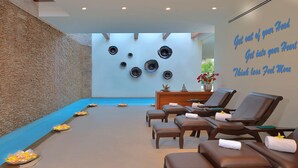 A spa room with a stone wall, a reception desk, and several massage chairs. - Radisson Hotel Khajuraho (Rajnagar)