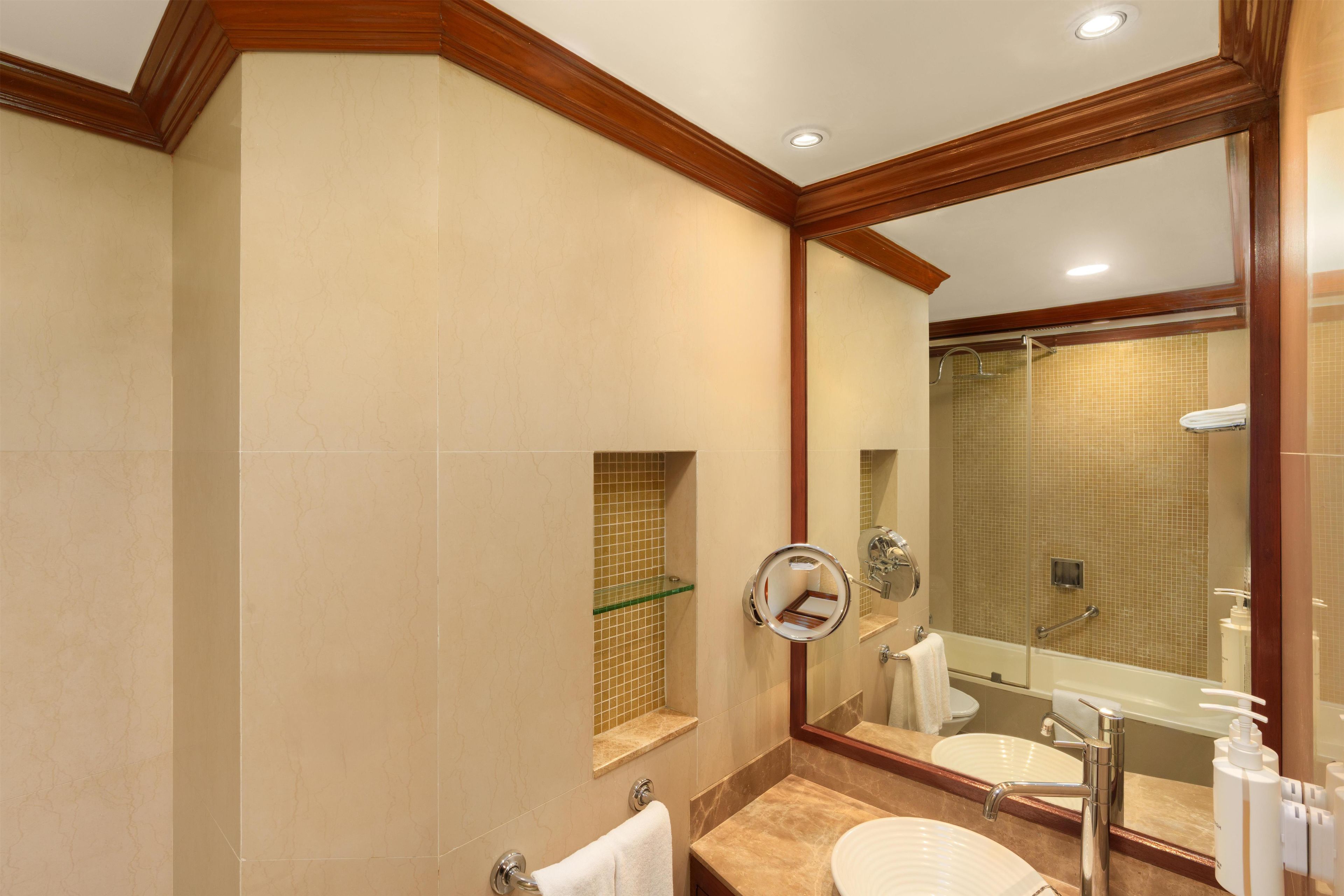 A bathroom with a large mirror, a sink, and a shower.