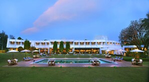 A hotel with a pool, outdoor seating, and a well-maintained garden. - Radisson Hotel Khajuraho (Rajnagar)