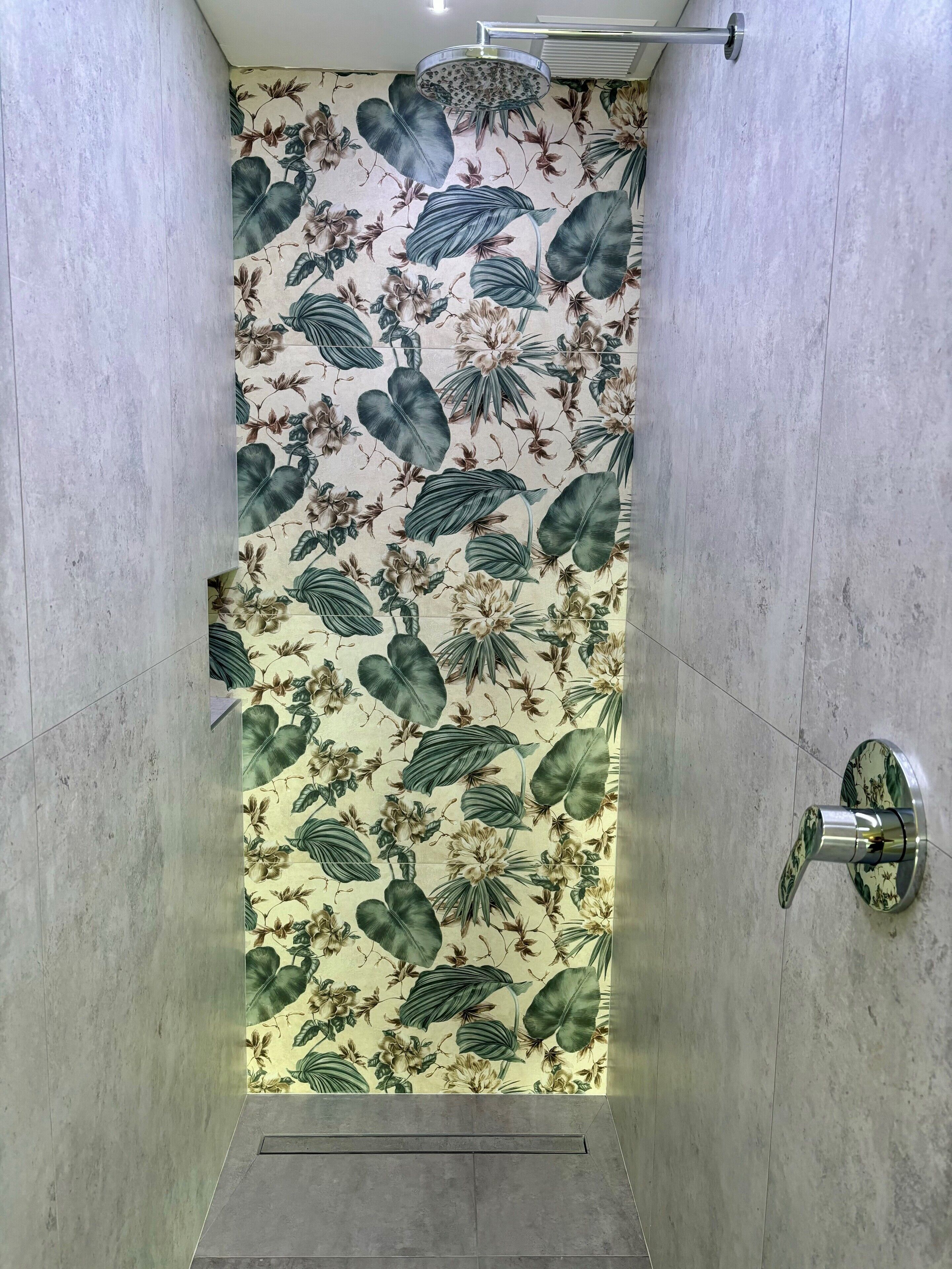 A shower with a floral wallpaper design and a modern faucet.