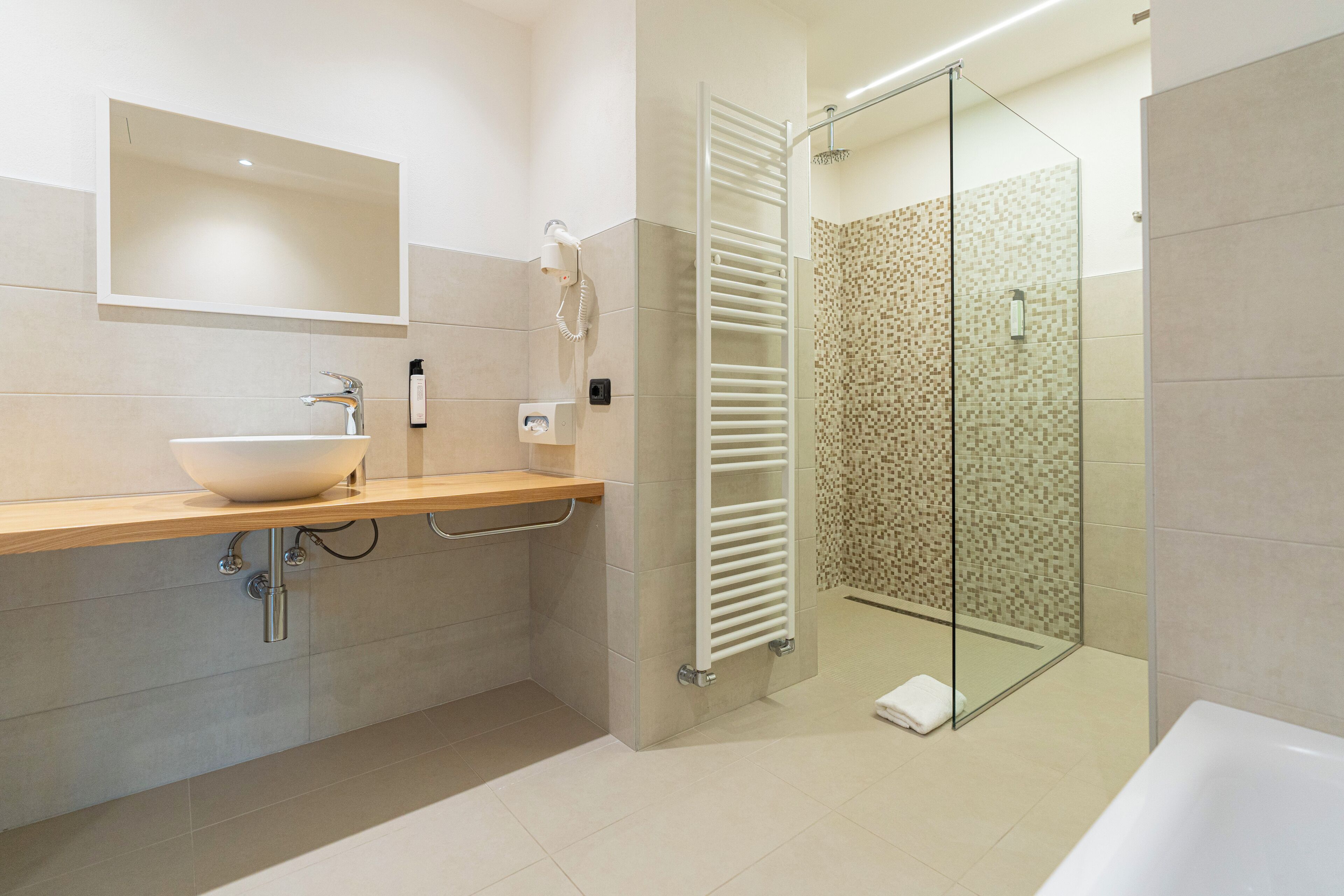 A modern bathroom with a large sink, a glass shower enclosure, and a towel rack.
