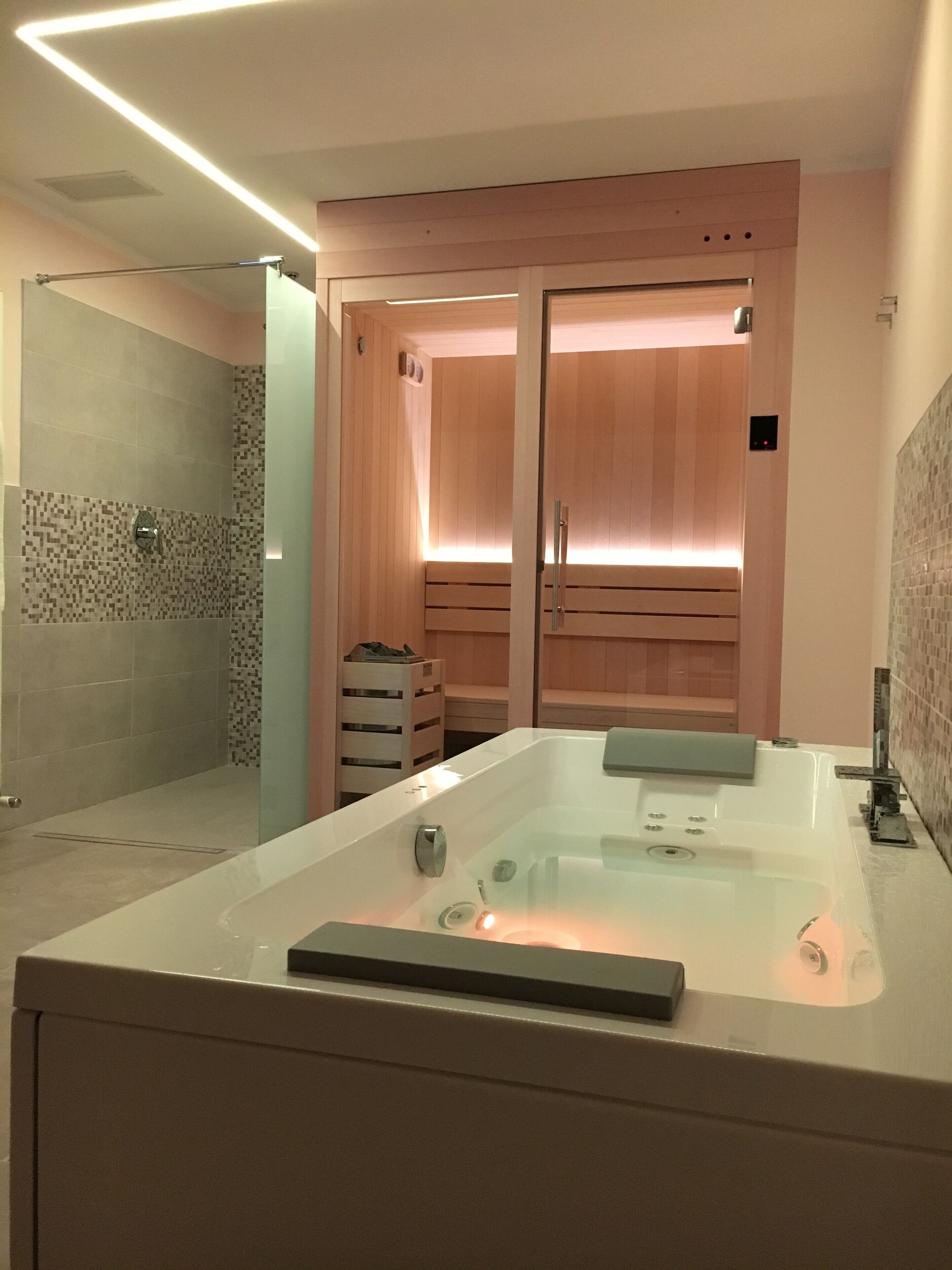 A modern bathroom with a large bathtub, a shower area, and wooden cabinets.