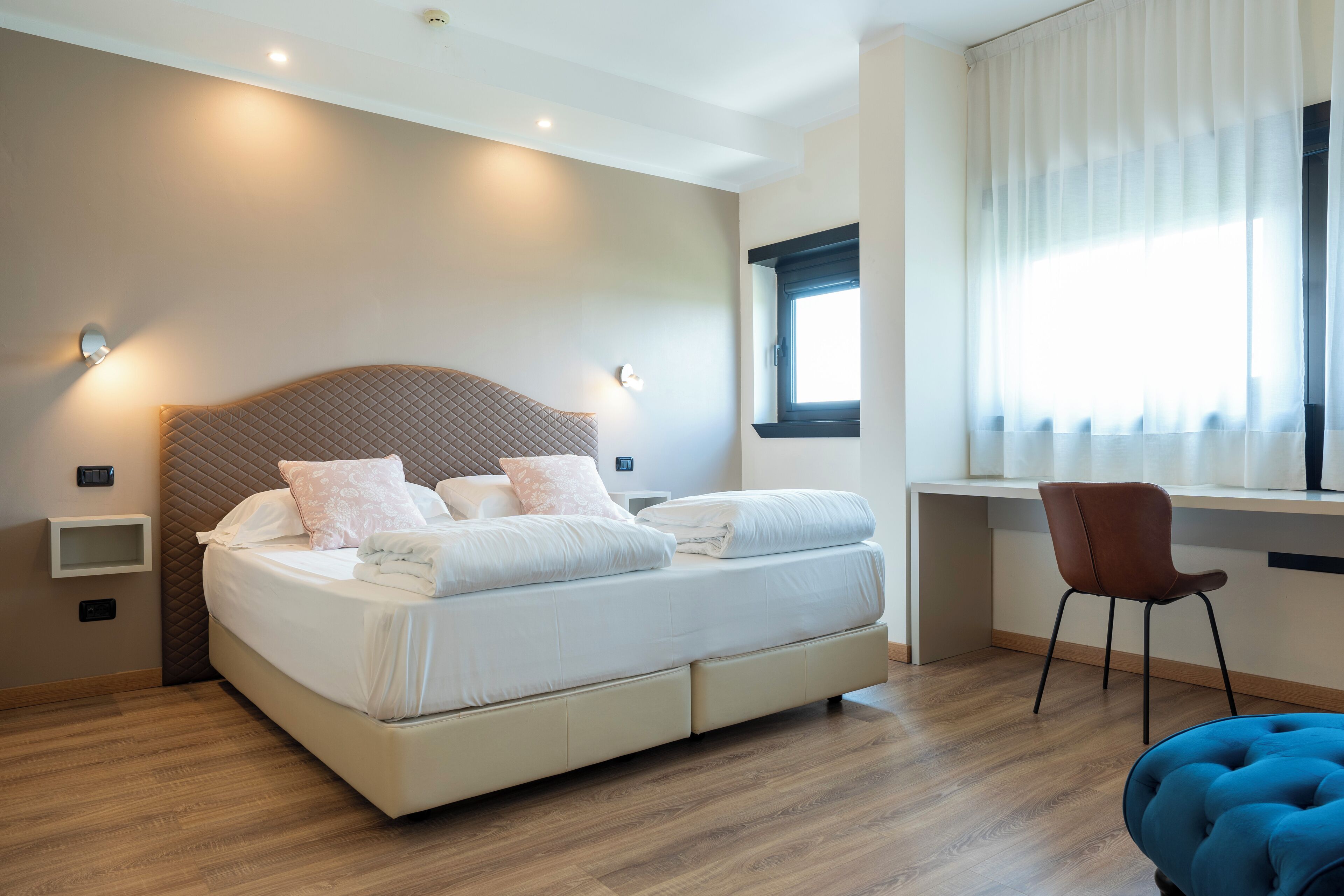 Un dormitorio moderno con una cama grande, mesitas de noche, un escritorio y una silla.