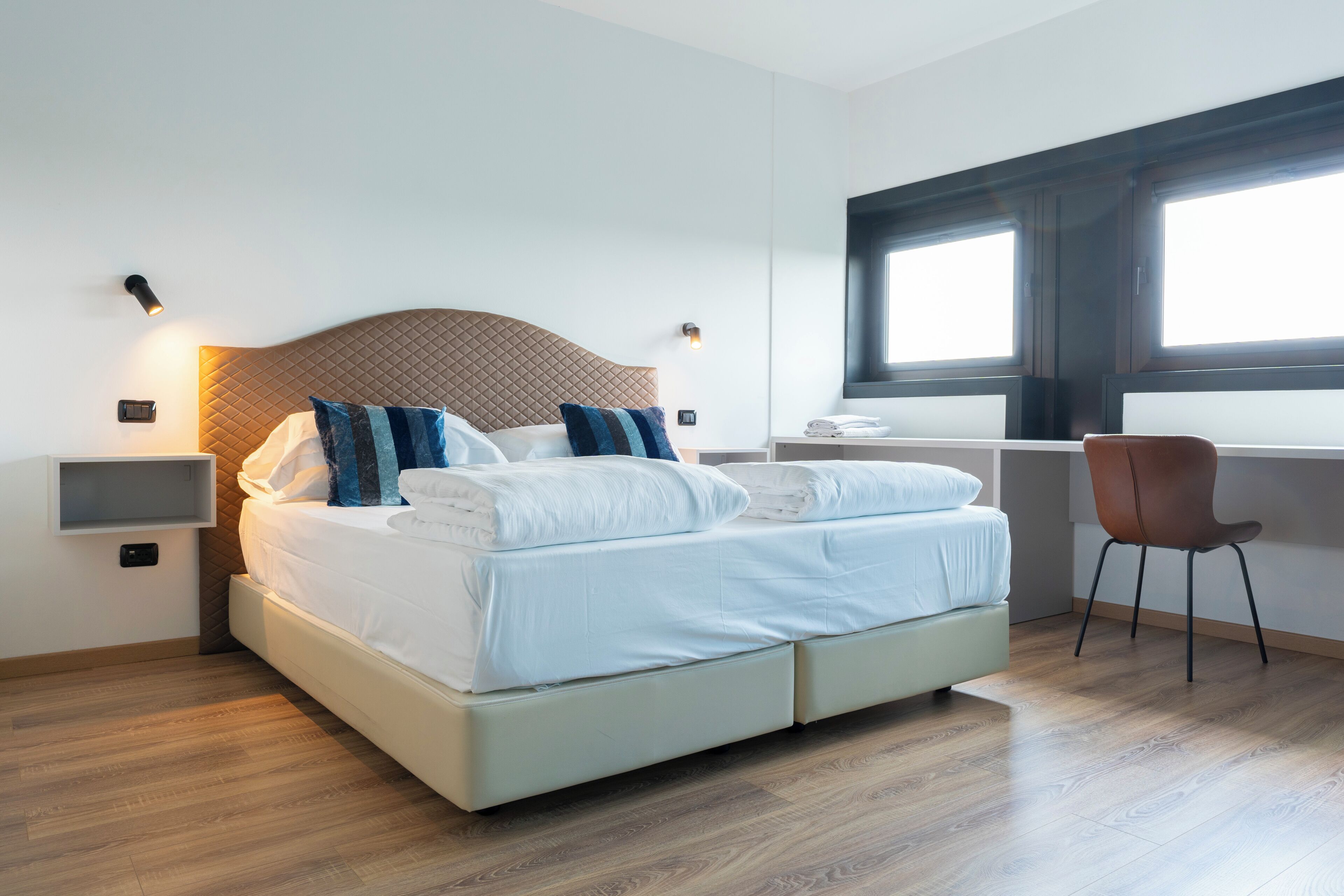Habitación de hotel moderna con una cama grande, un escritorio y una ventana con persianas.